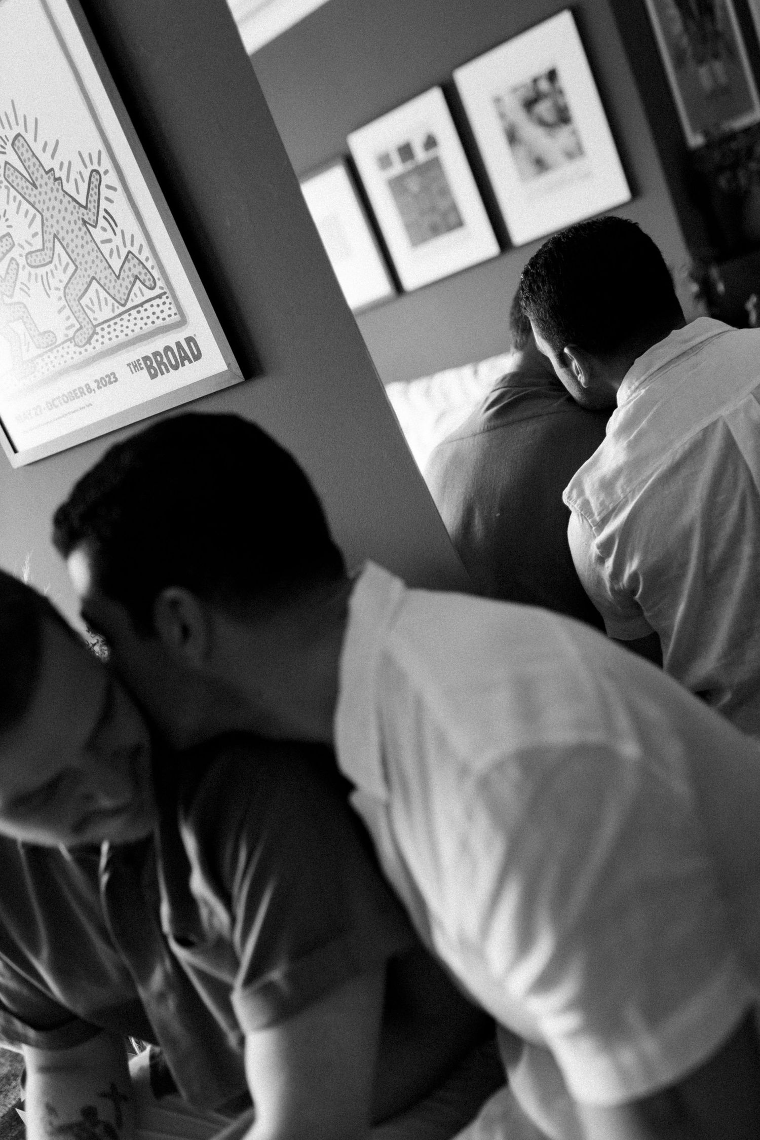 Blurred figures in motion against a wall with framed artwork.