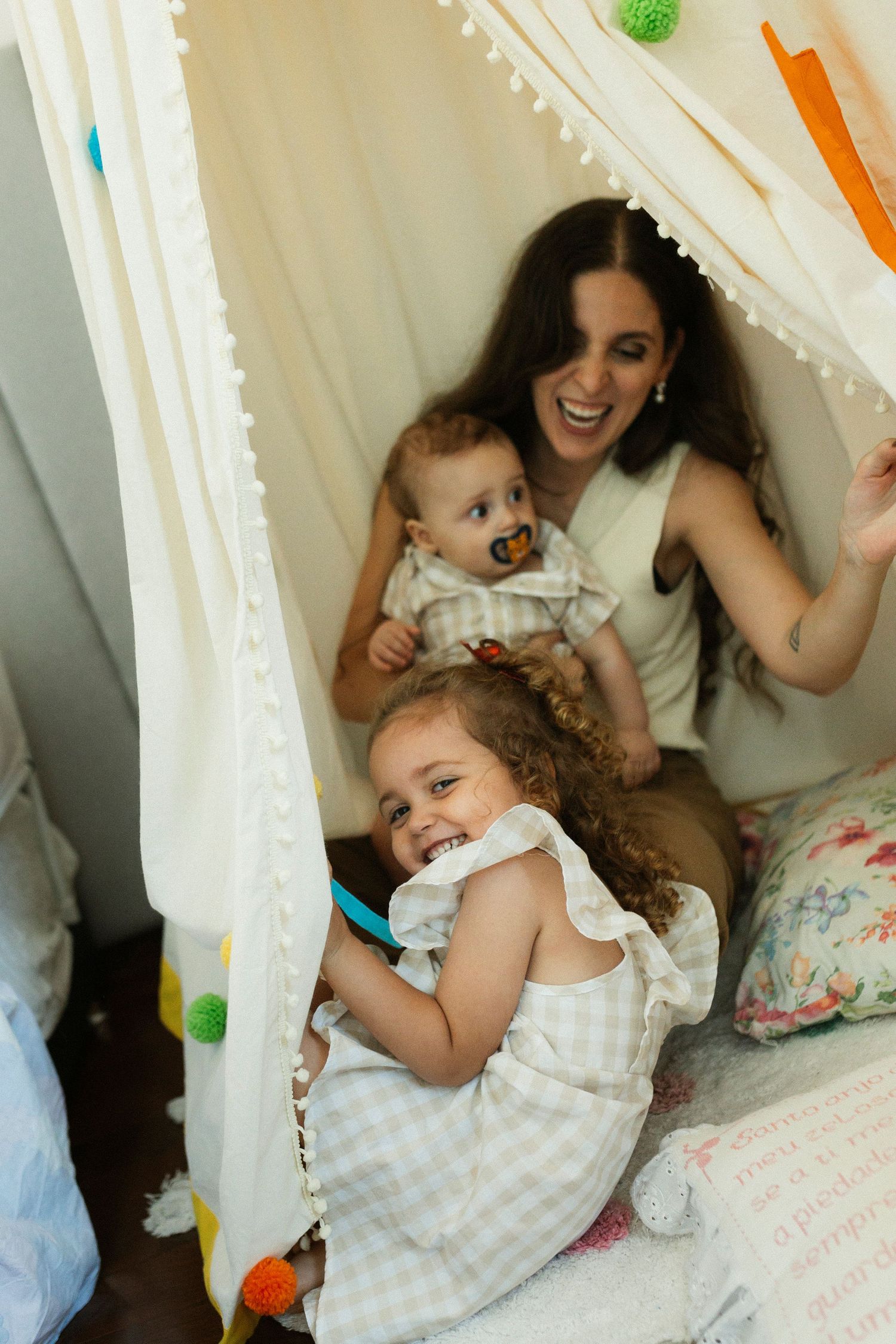Playful moments captured in a cozy indoor fort decorated with string lights and soft textiles.