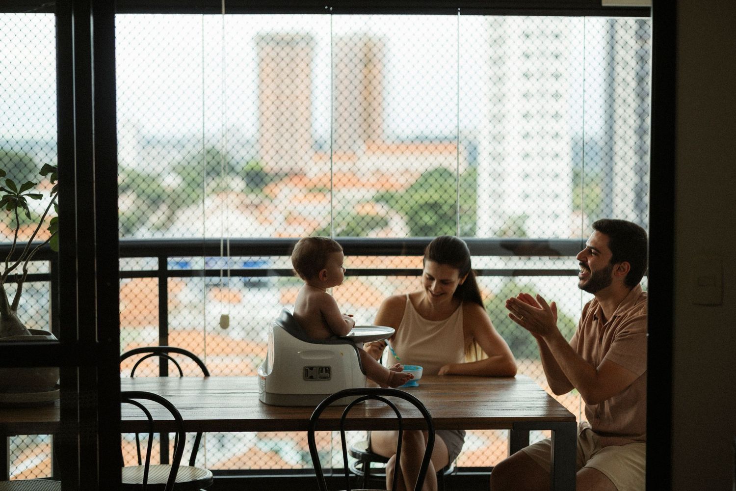 People sit at tables in a bright cafe space with large windows overlooking a cityscape.