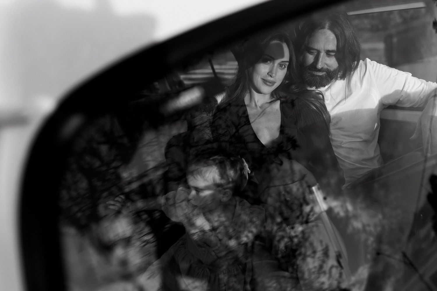 Black and white reflection of a couple in a car side mirror, romantic outdoor portrait photography.