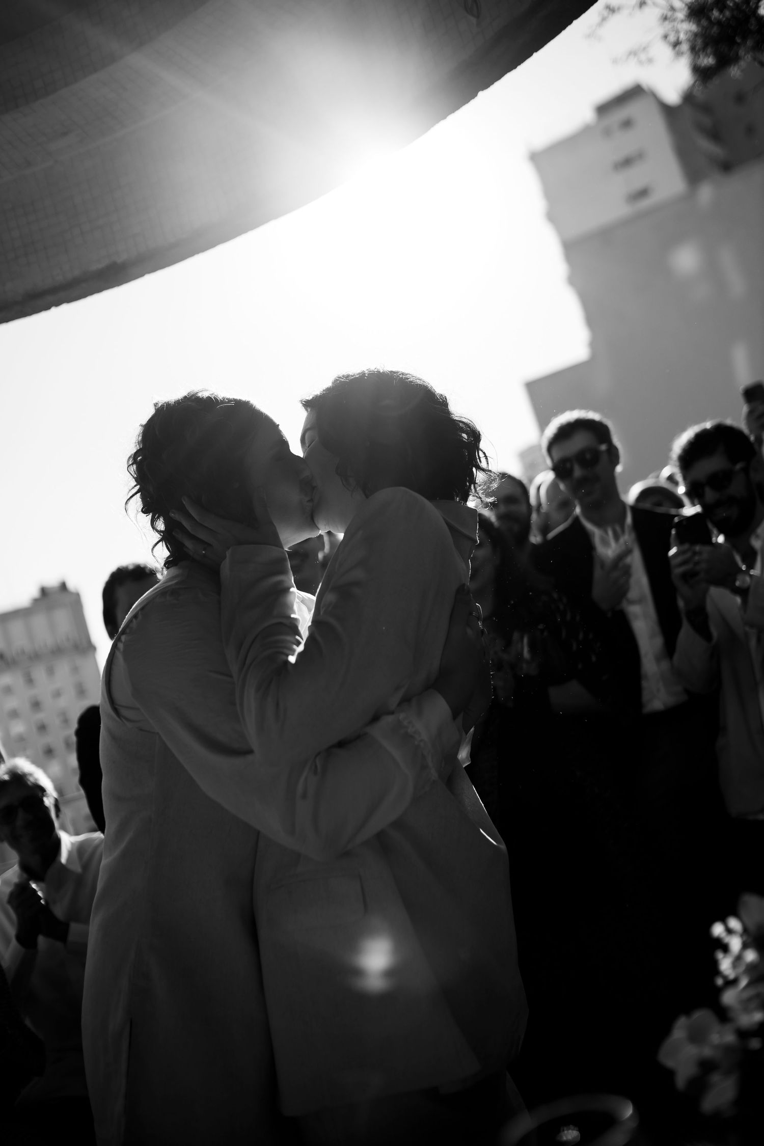 Silhouetted couple sharing an intimate moment surrounded by onlookers at an event.