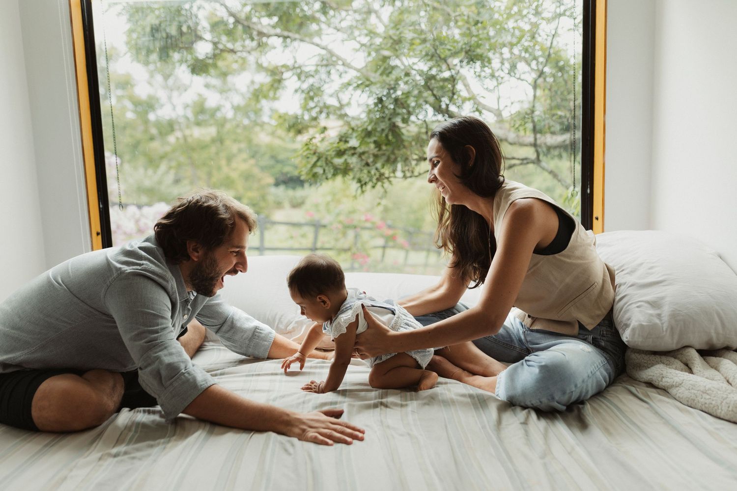 Family members lying down together playfully on a white surface in a sequence of candid shots.