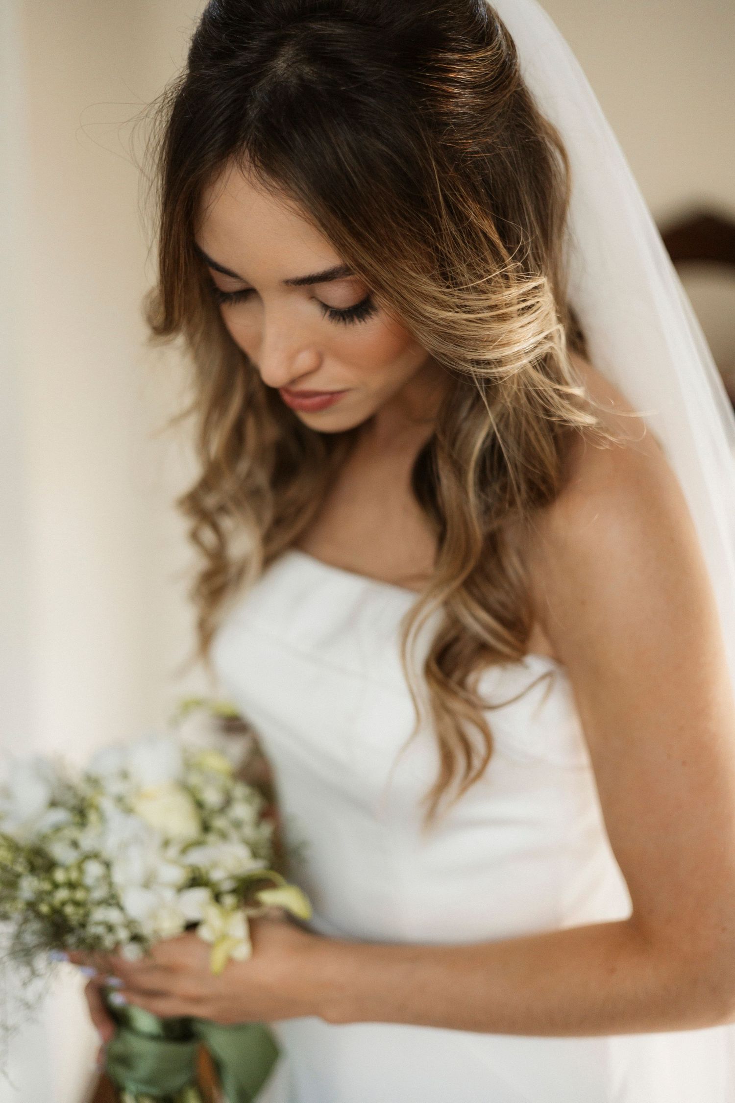 Elegant white bridal gown details with delicate bouquet of fresh flowers.
