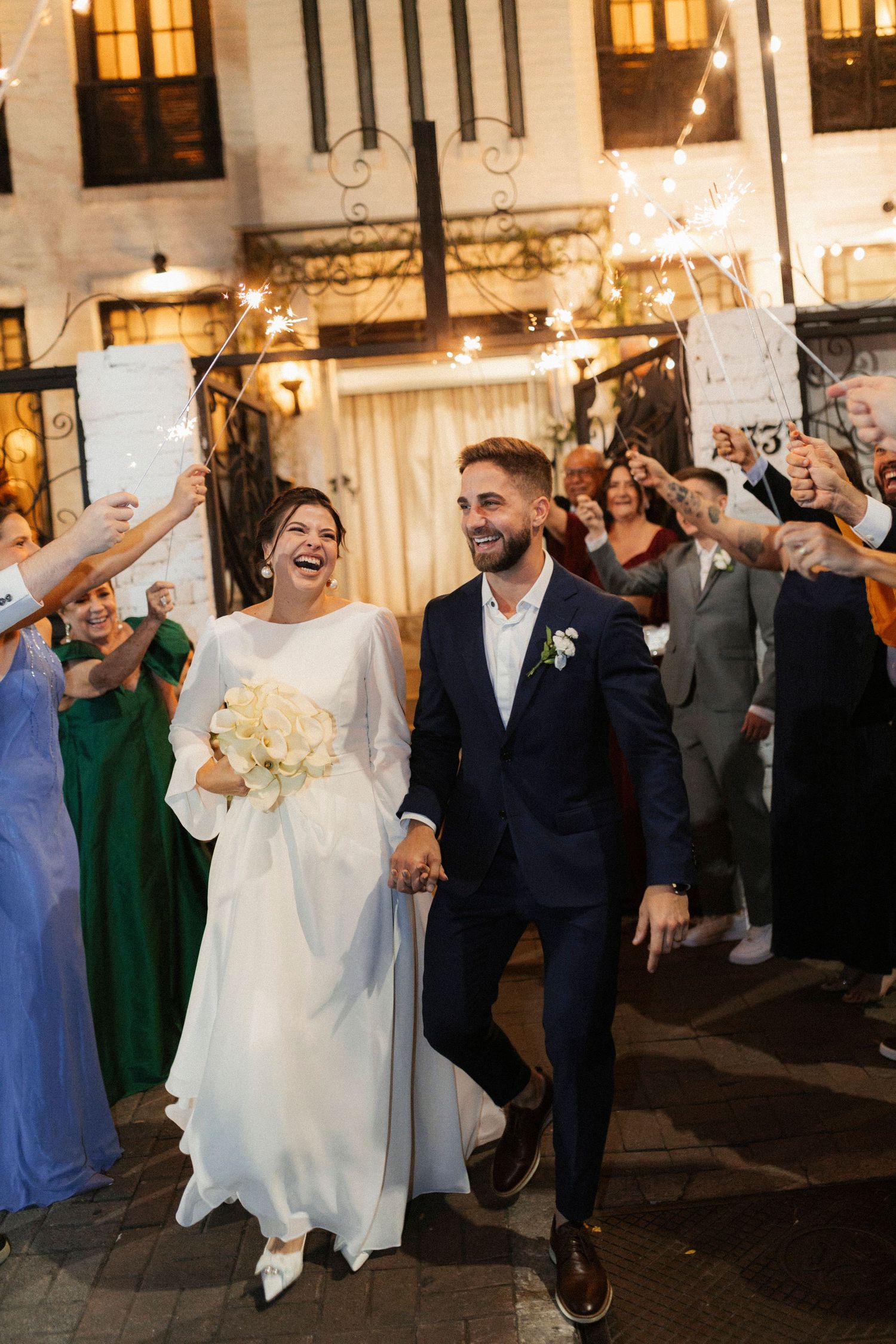 Wedding party dancing and celebrating joyfully at an evening reception with warm lighting.