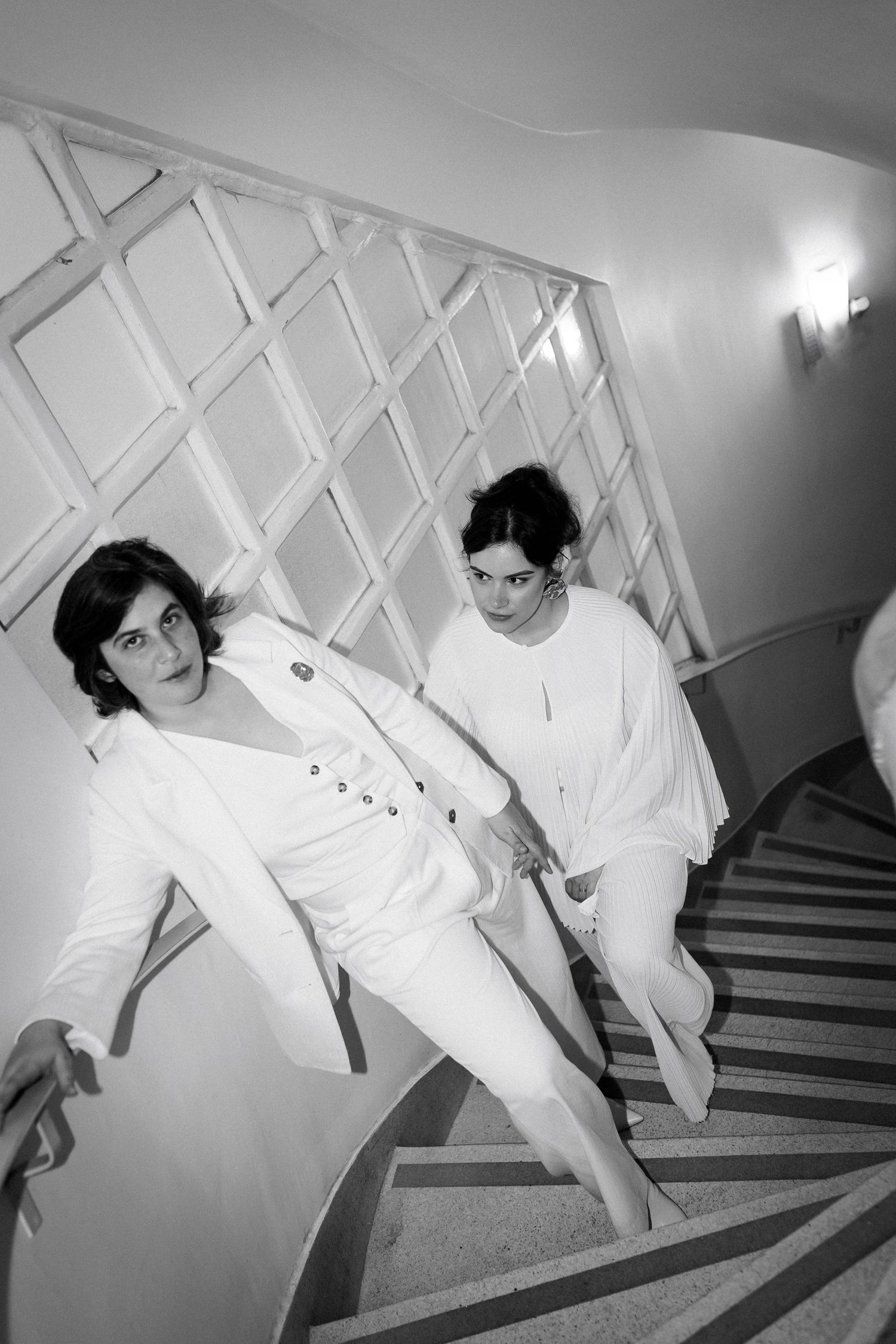 Artistic black and white photo sequence showing playful poses on staircase with geometric wall pattern.