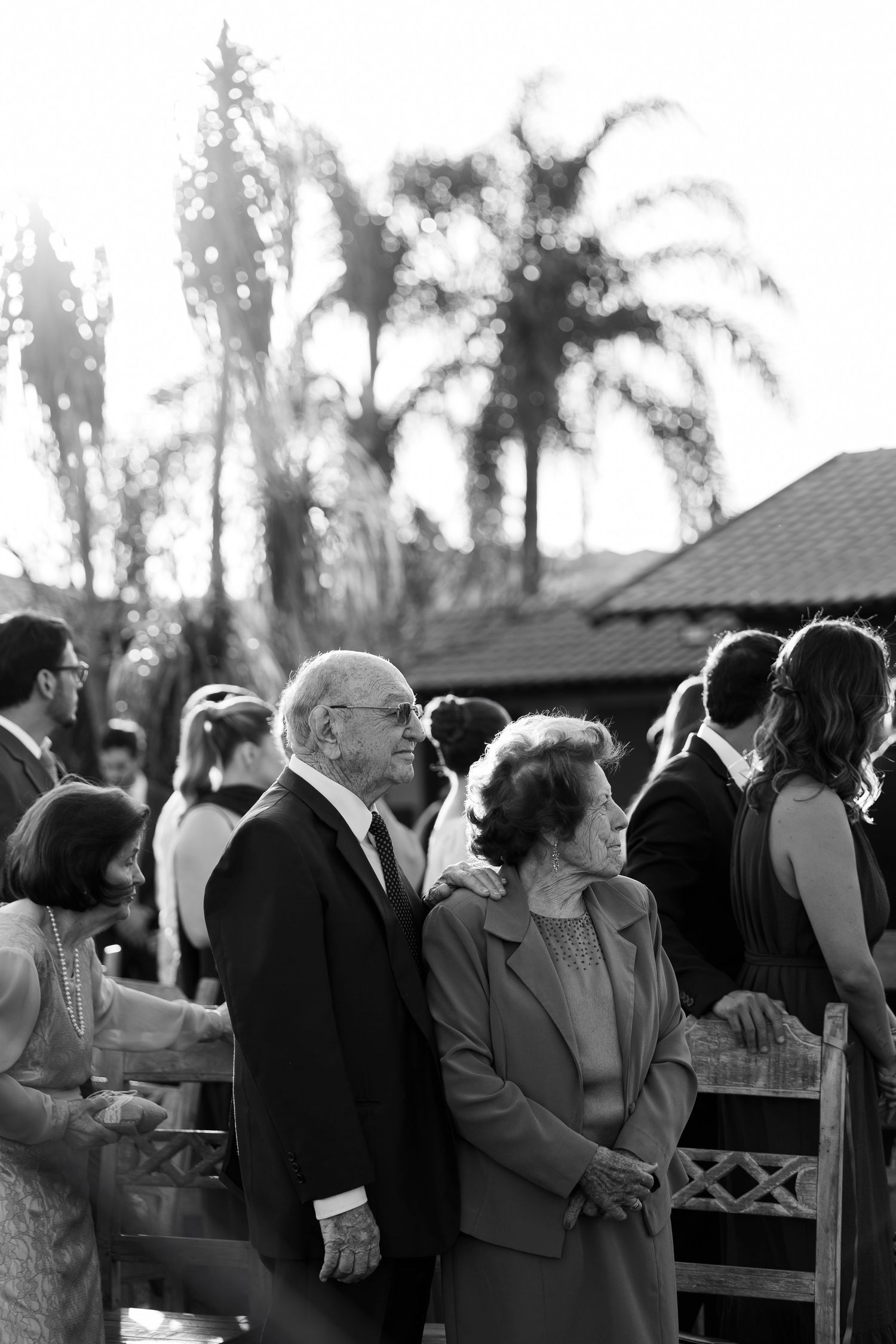 Black and white photo of wedding guests gathered outdoors during ceremony.