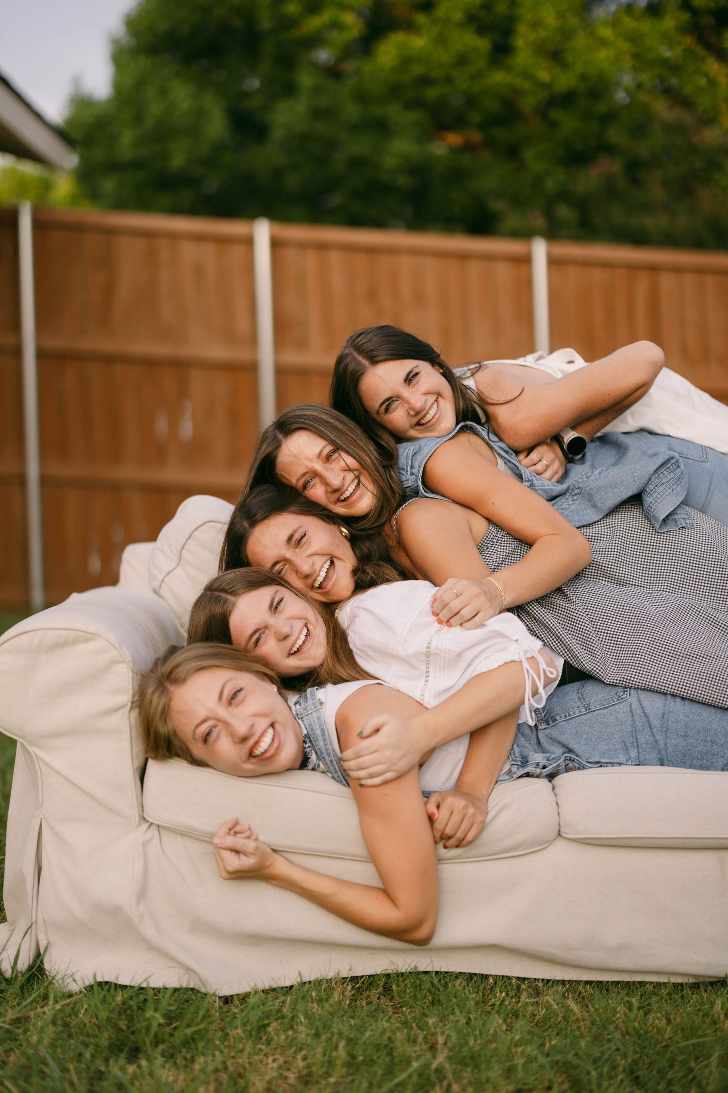 Friends lounging together on a couch outdoors, sharing laughter and embraces.