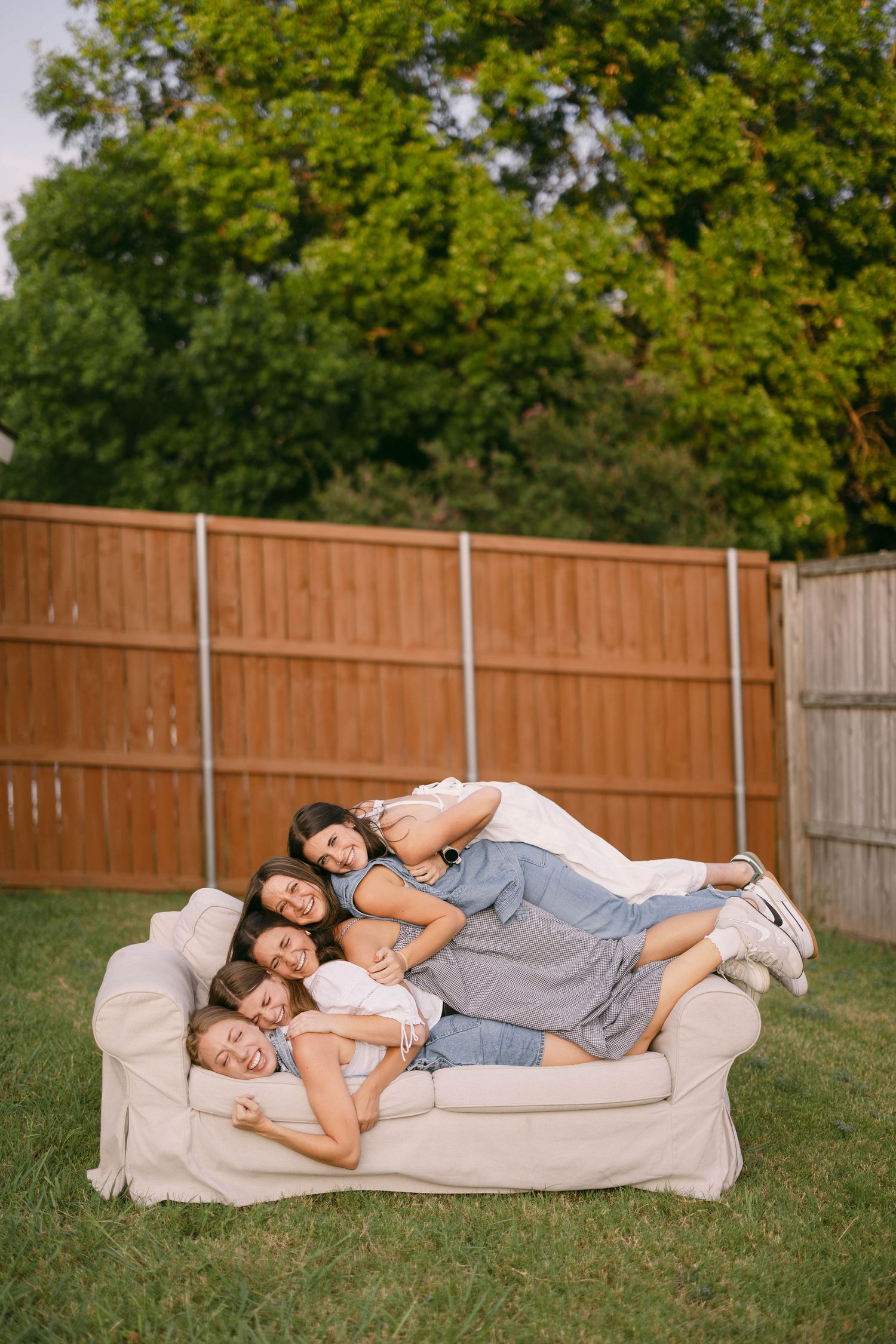 Friends relaxing together on a cozy beige couch outdoors on grass.