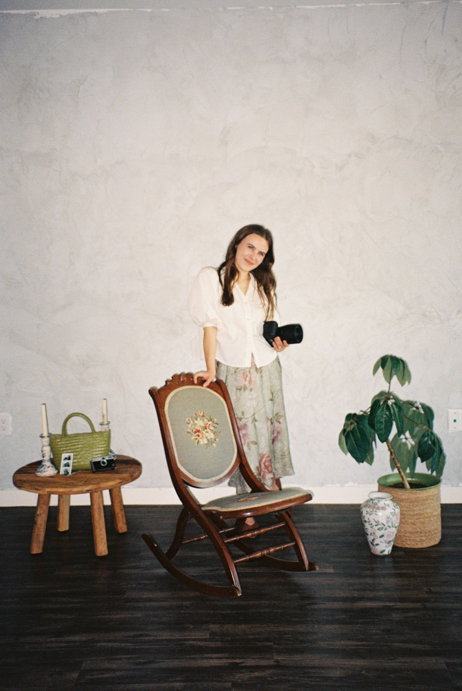 Vintage wooden chairs and potted plants arranged against a white wall in a minimalist setting.