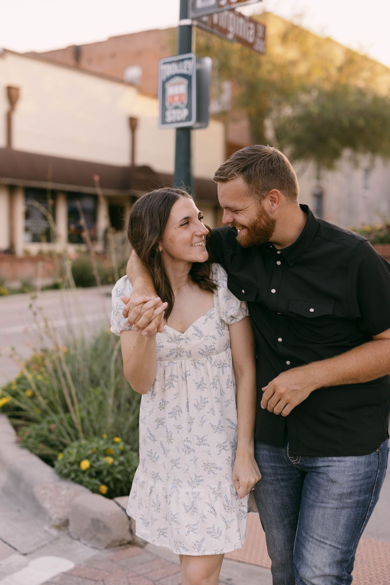 Couple in black and white outfits sharing affectionate moments on a city street.