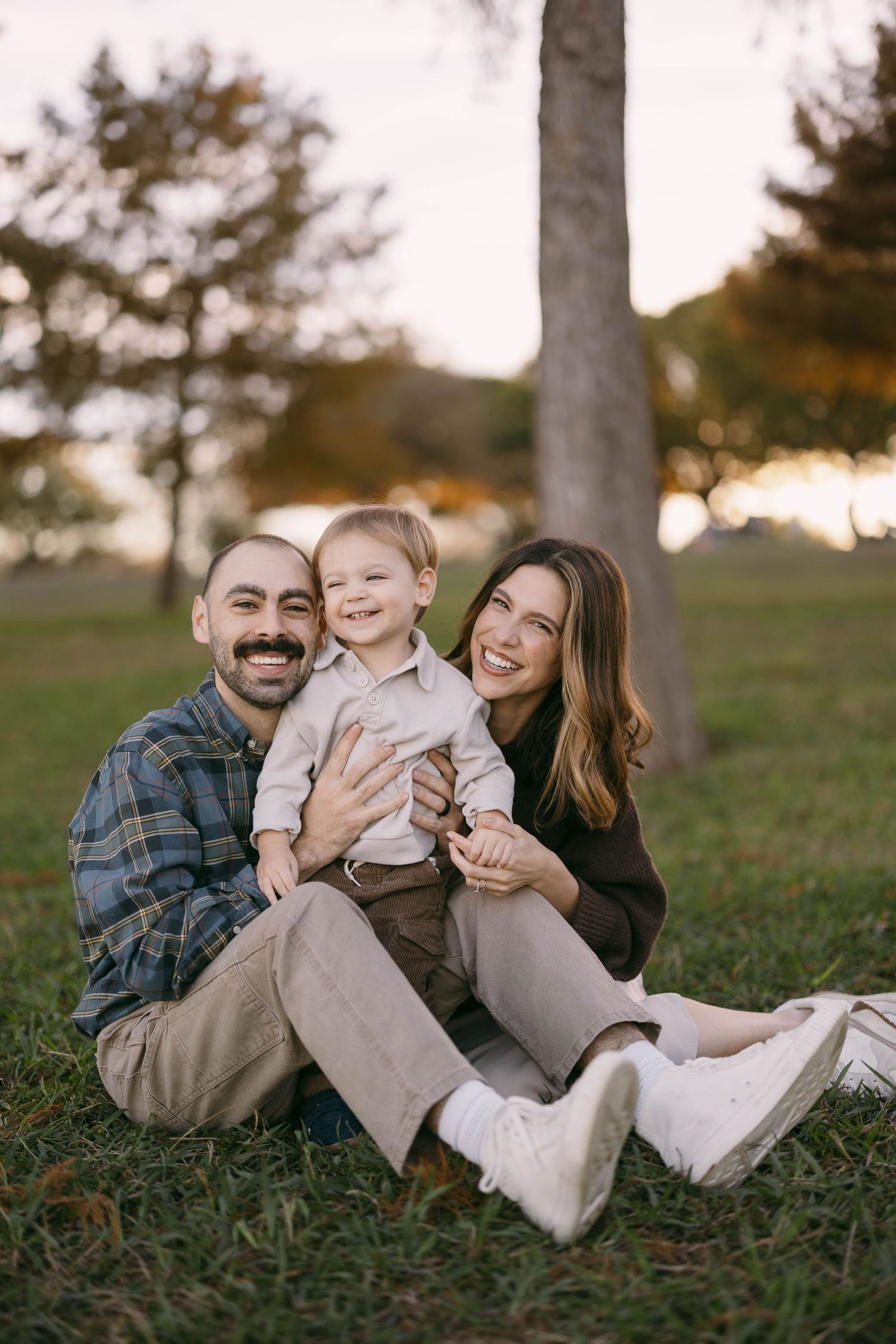 Family lying on grass during a casual outdoor photo session at sunset.