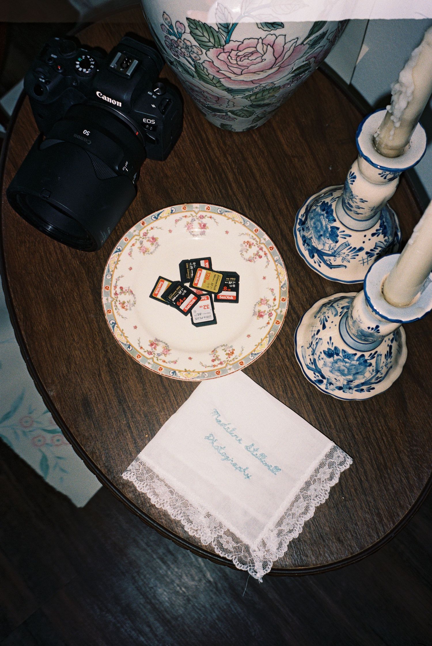 Antique decorative plates and lace doilies displayed on a wooden surface with vintage photographs.