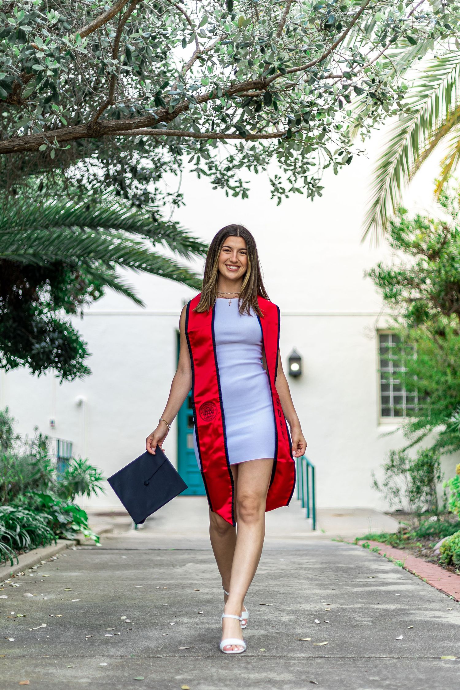 Graduate walking and posing along covered walkway in celebratory shots.