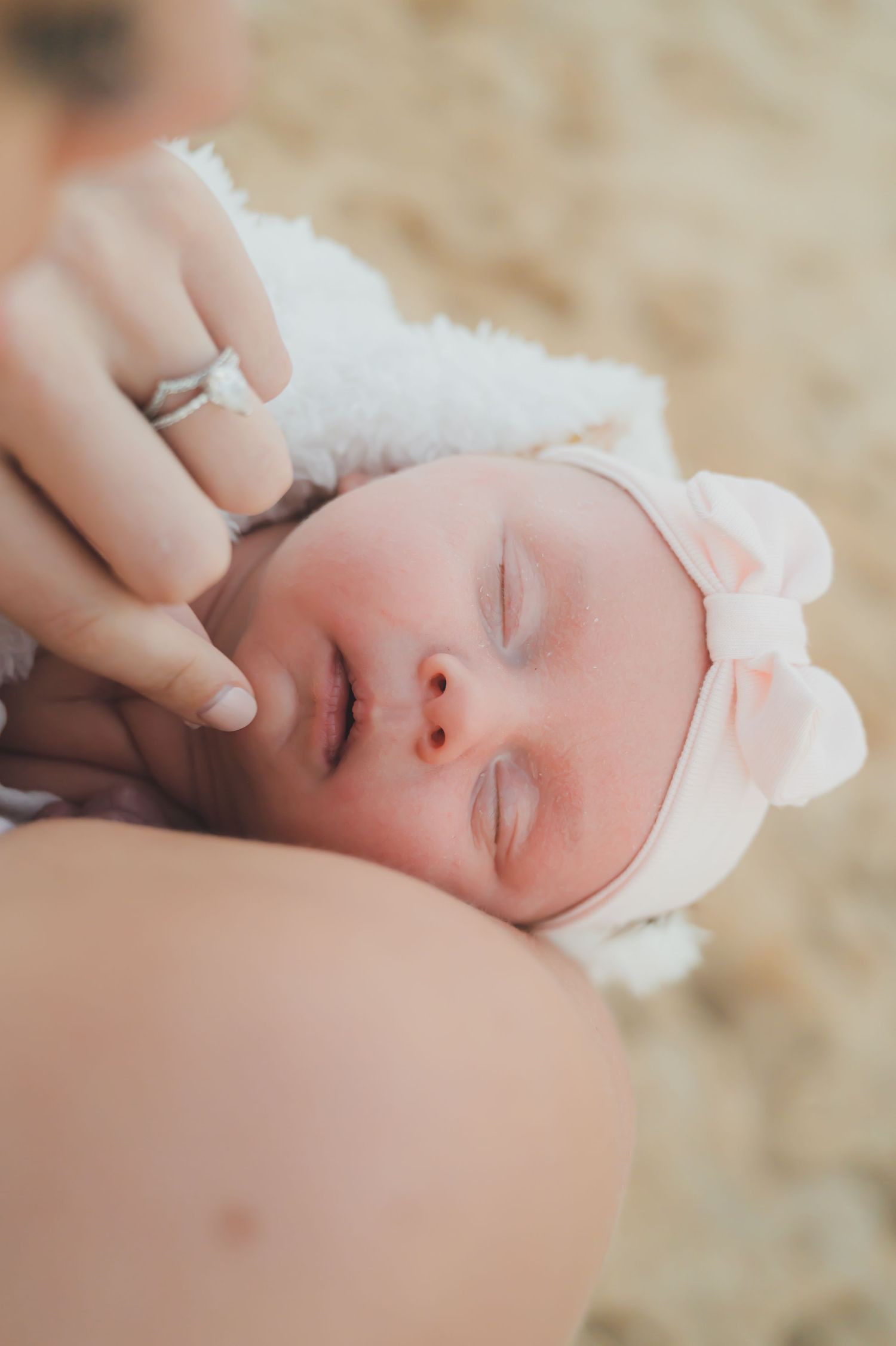 Newborn photography session with a detailed photo of a baby on the beach in her mothers arms