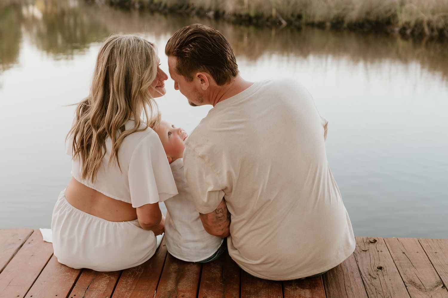 Family cuddled with kid looking at mom and dad for photograph in Yulee, Florida