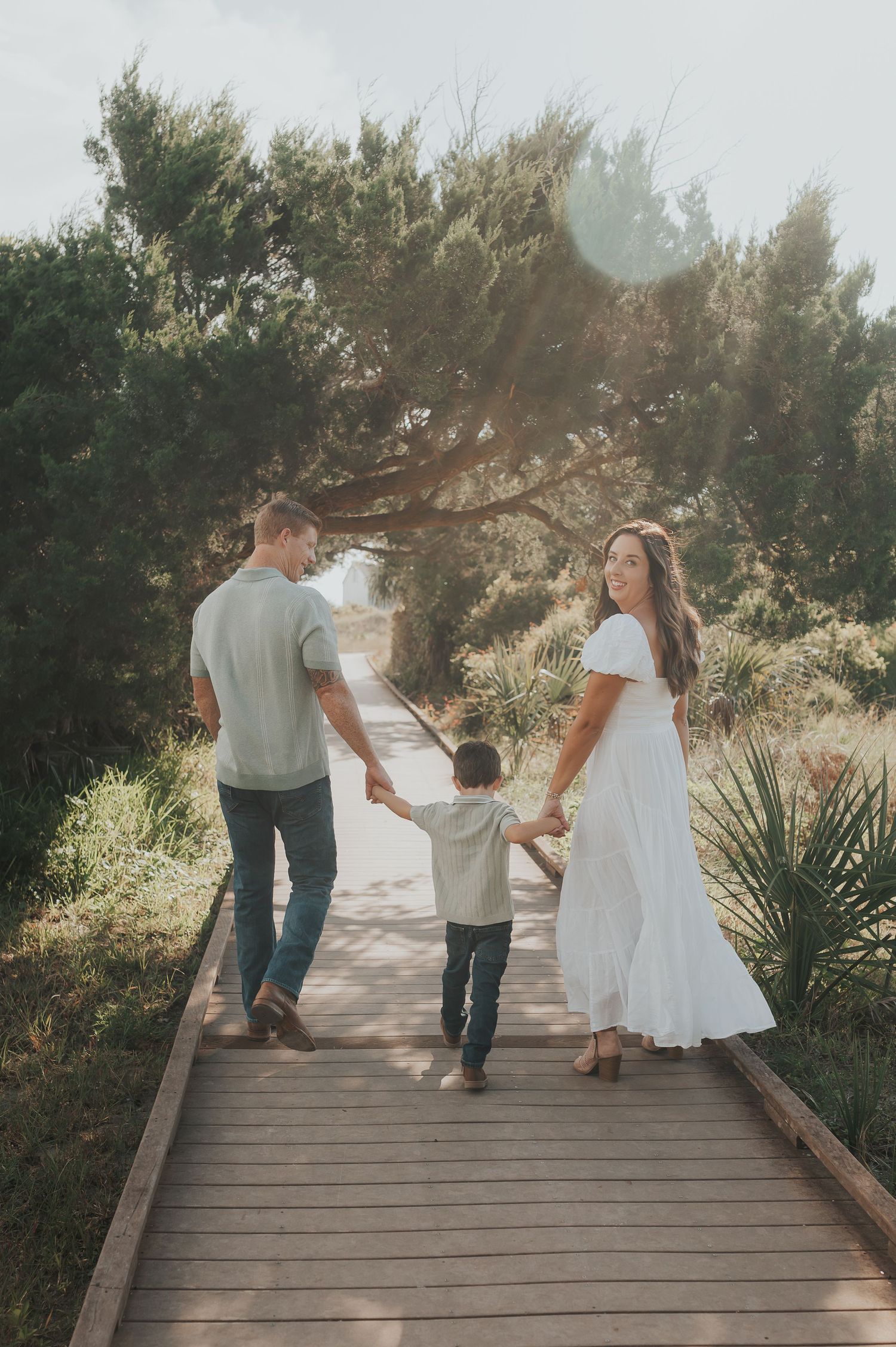 Family photo at Ft Clinch Beach in Fernandina Beach Florida with family holding hands and mom looking back at camera while dad looks at kid