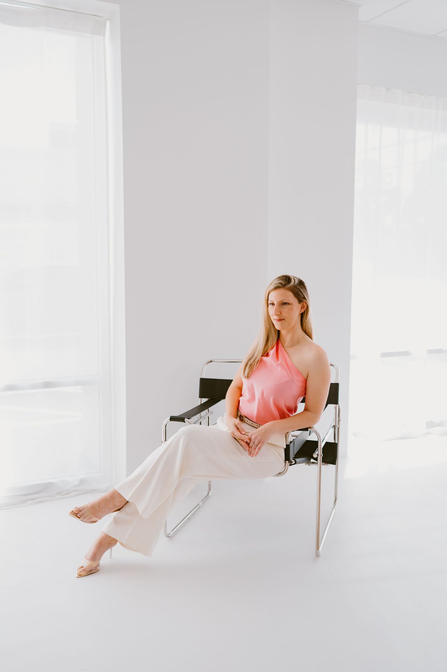 Content creator branding session of woman in bright pink top in white studio featuring side profile and powerful look
