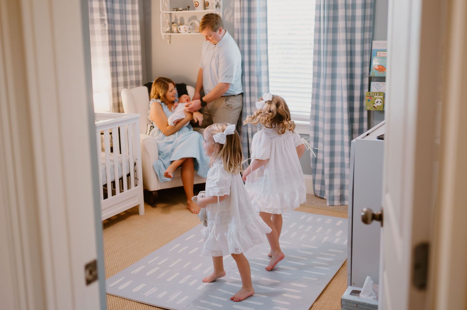 In home newborn photograph with siblings playing while parents take care of newborn in Amelia Island Florida