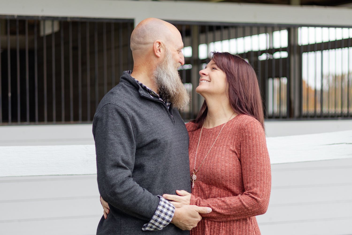 Couple in casual attire sharing a romantic moment against an industrial backdrop.
