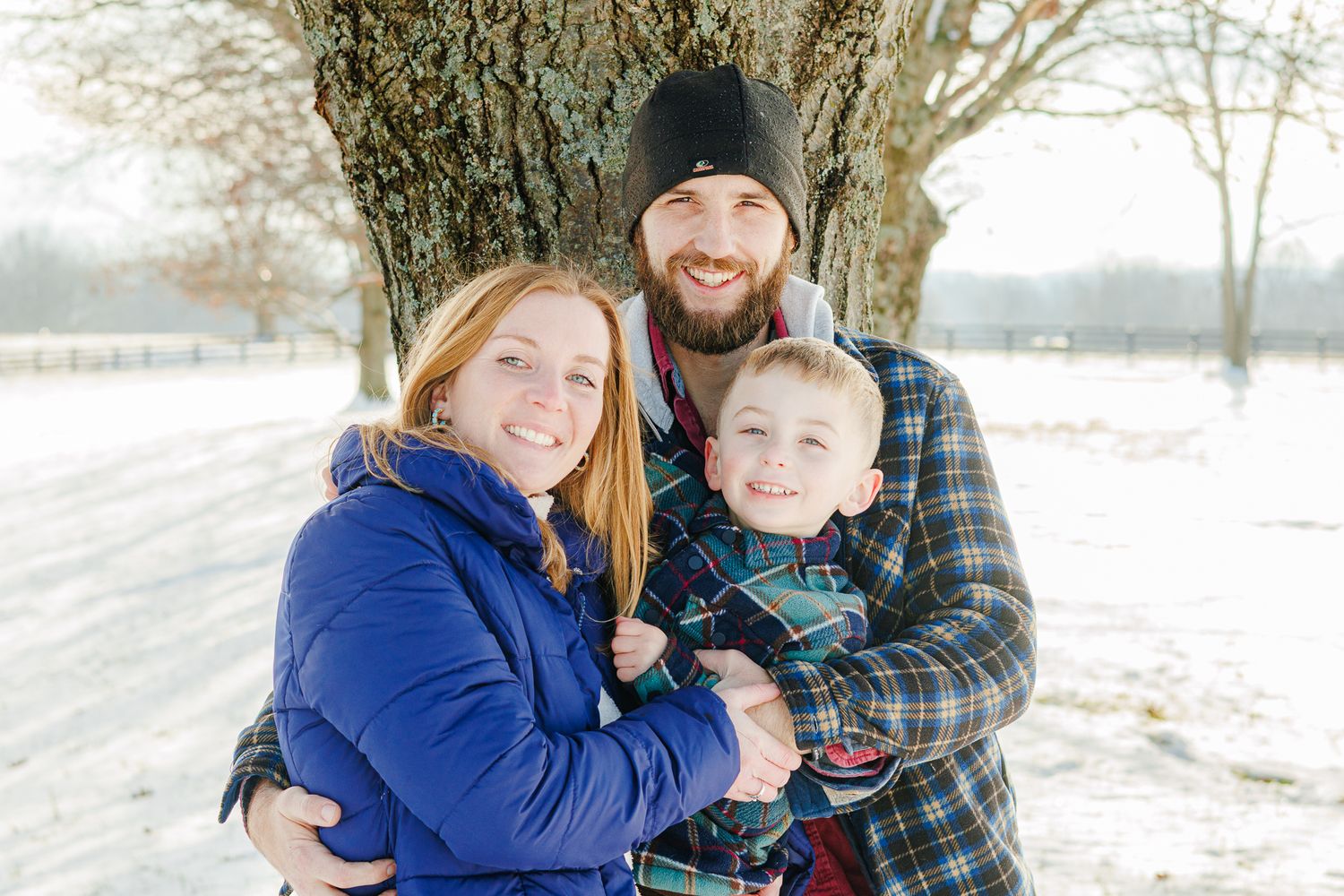 A winter family scene with snow-covered trees in the background.