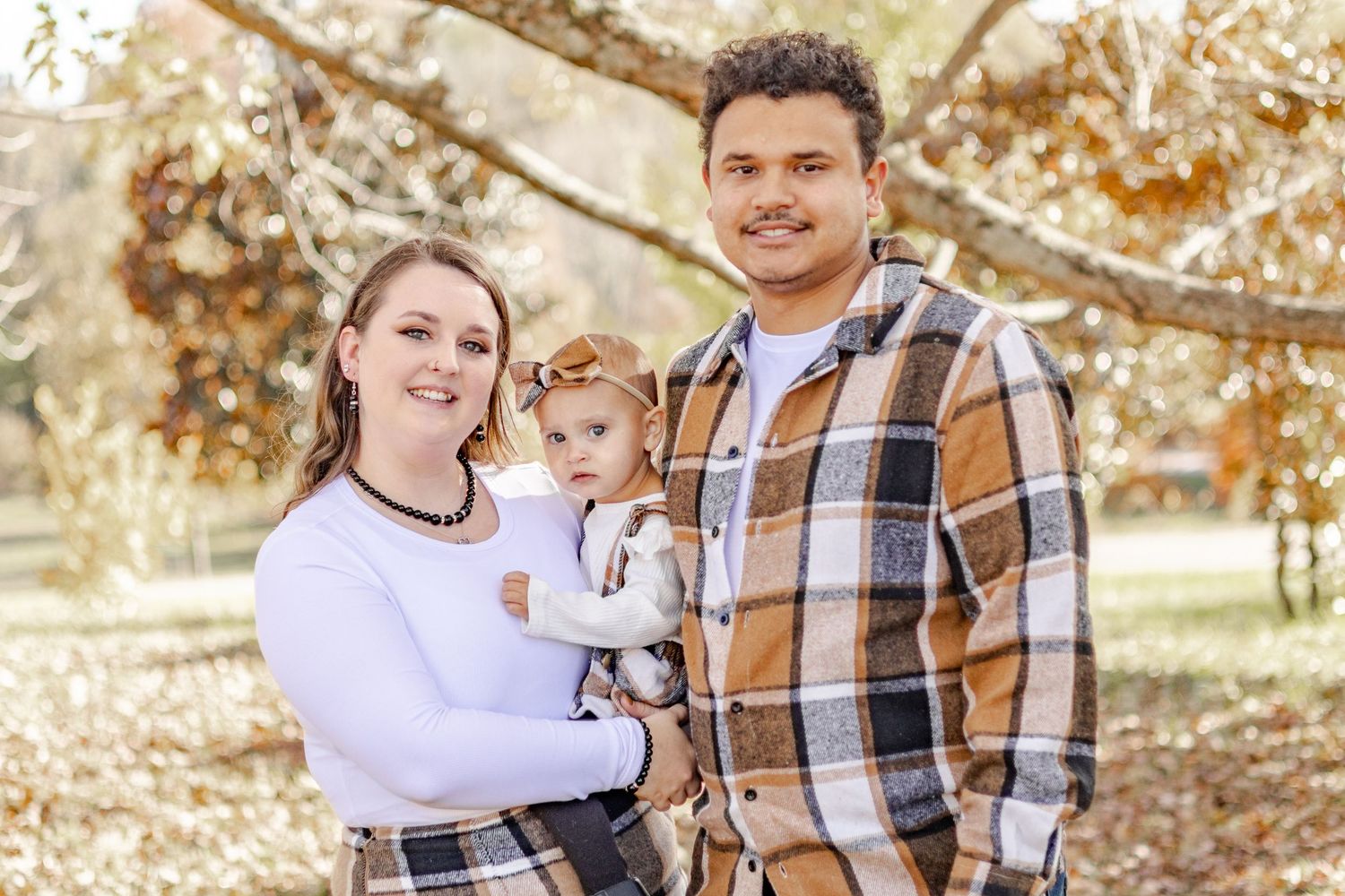 Family enjoying a warm autumn day together in a park setting with golden leaves and natural lighting.