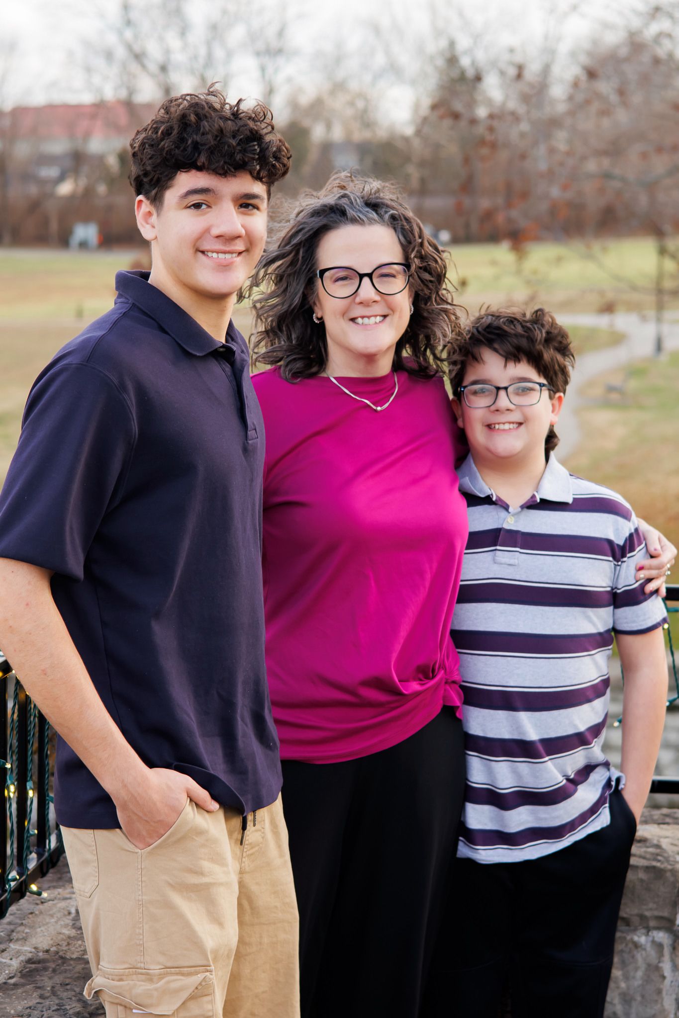 Three people pose together against a stone wall outdoors.