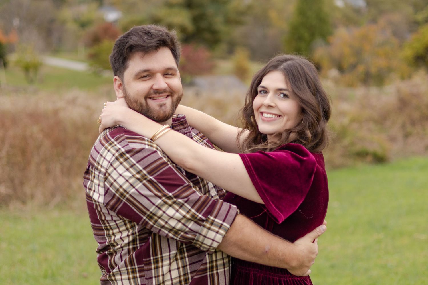 A couple shares an intimate moment in a grassy field during autumn.