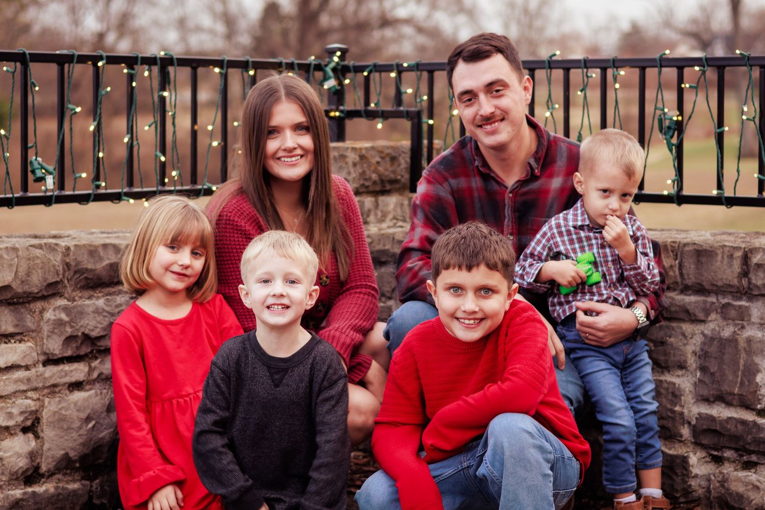 A casual family portrait by a stone wall in autumn weather.