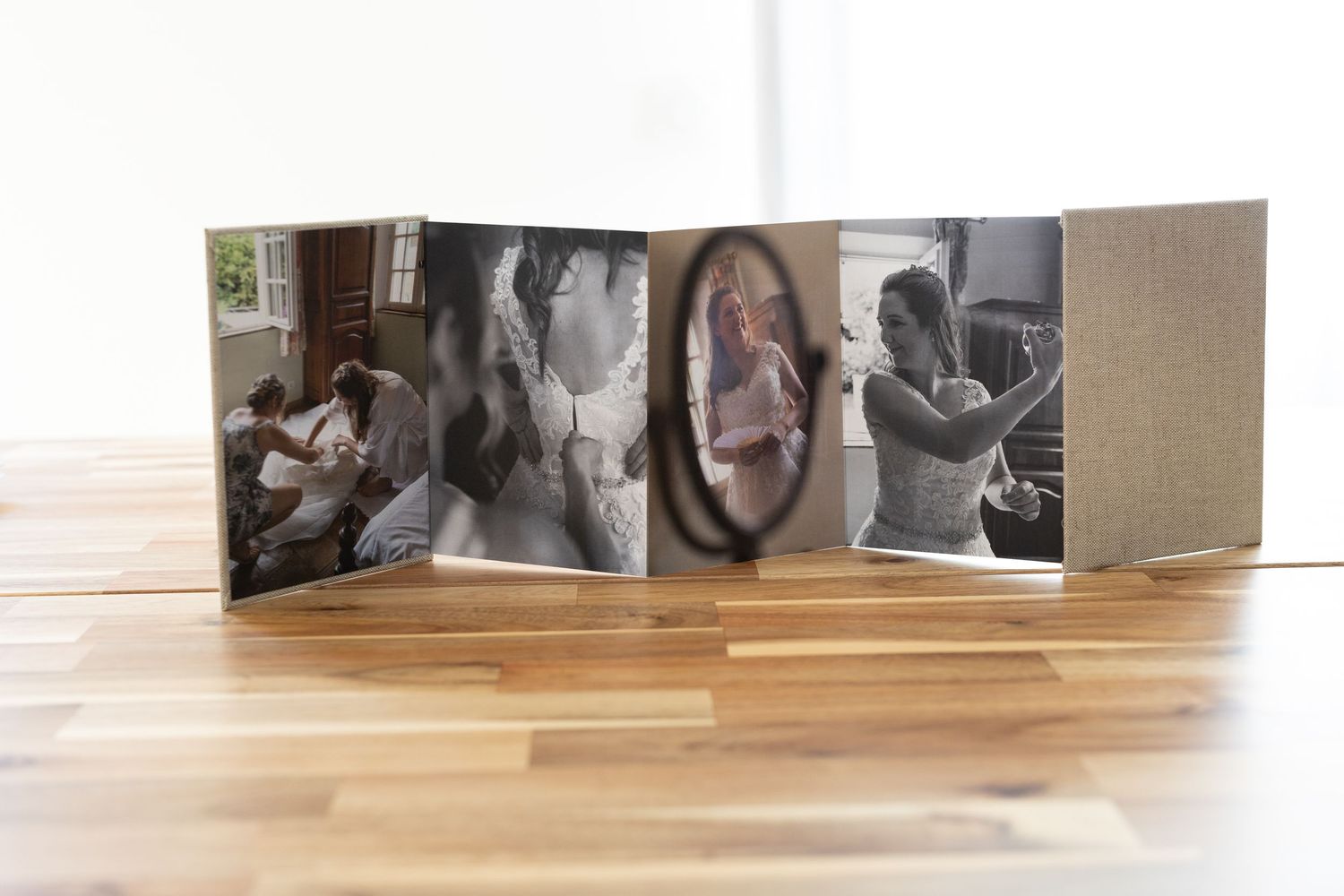 Livre photo en accordéon présentant plusieurs photographies prises sur le vif,en noir et blanc et en couleur, posé ouvert sur un sol en bois