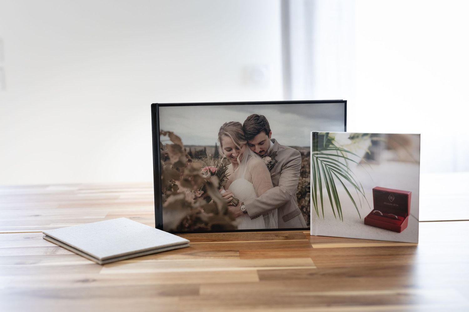 Album photo de mariage et portrait du couple encadré, disposés sur une table en bois avec d'élégants coffrets de présentation.