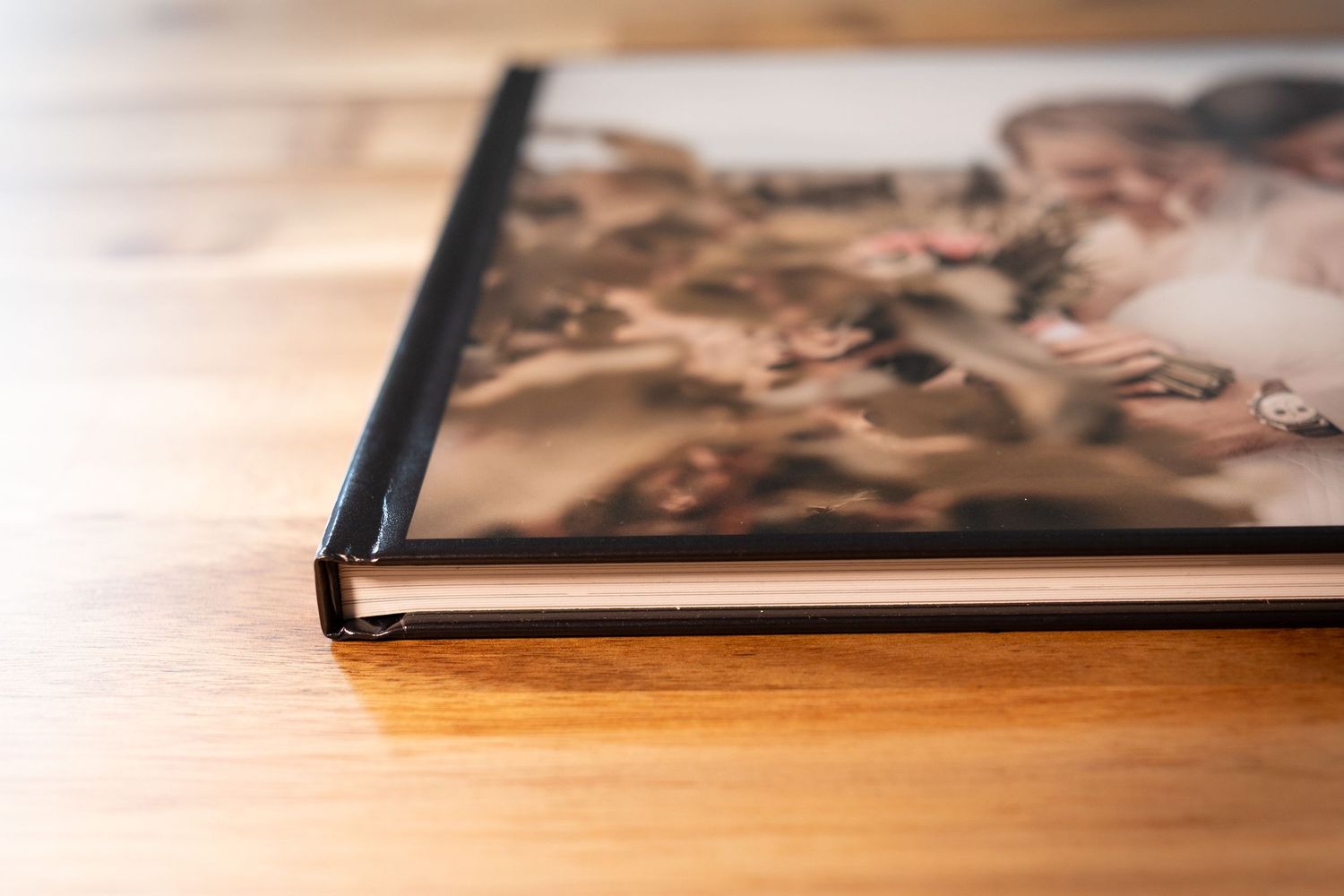Gros plan sur un livre photo à couverture rigide et brillante, orné d'un portrait de famille, posé sur une surface en bois.