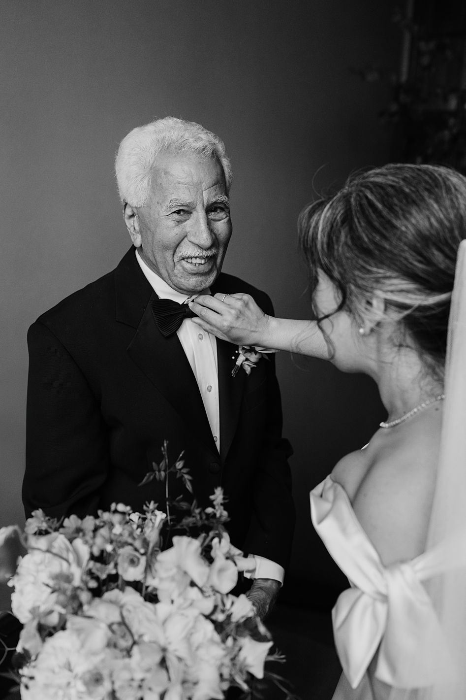 Emotional black and white moment between bride and elderly grandfather smiling at wedding celebration.