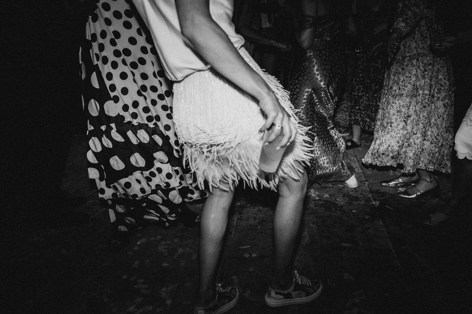 Black and white candid photo of guests dancing at a lively wedding reception party.