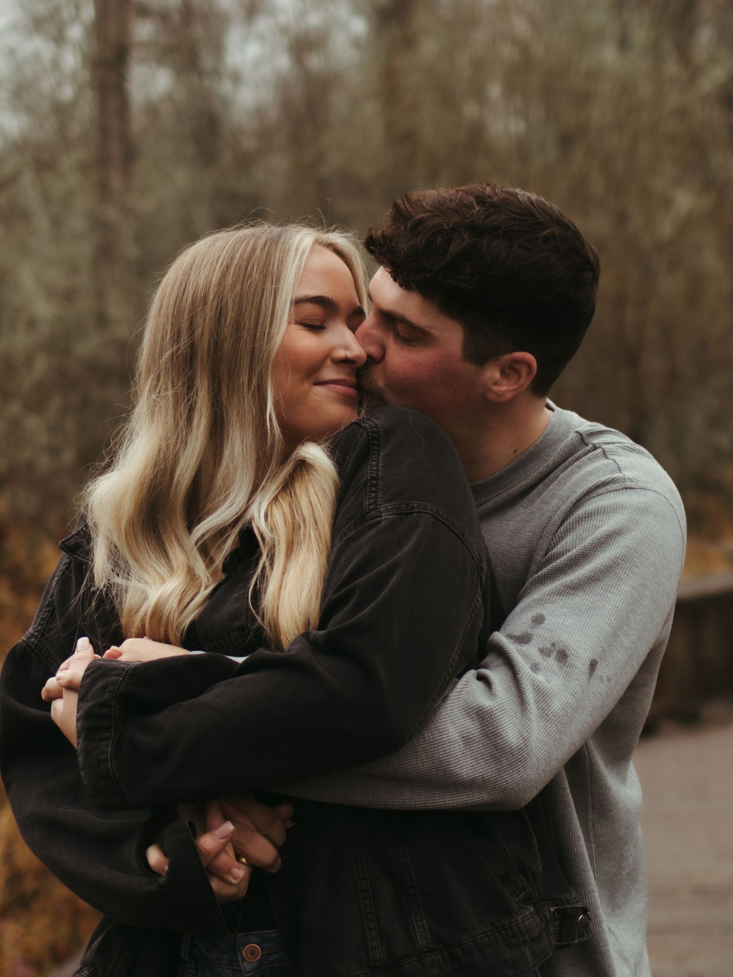 Couple in casual attire sharing affectionate moments in a natural setting.