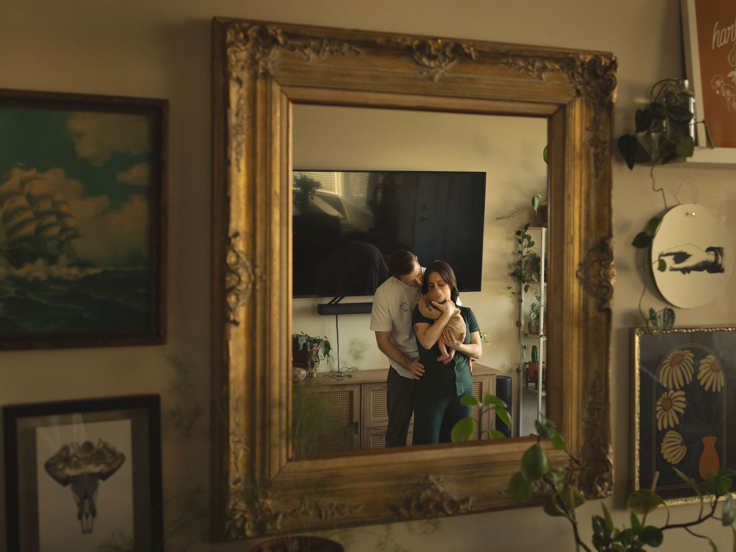 A romantic moment reflected in an ornate gold-framed mirror with artwork on the walls.