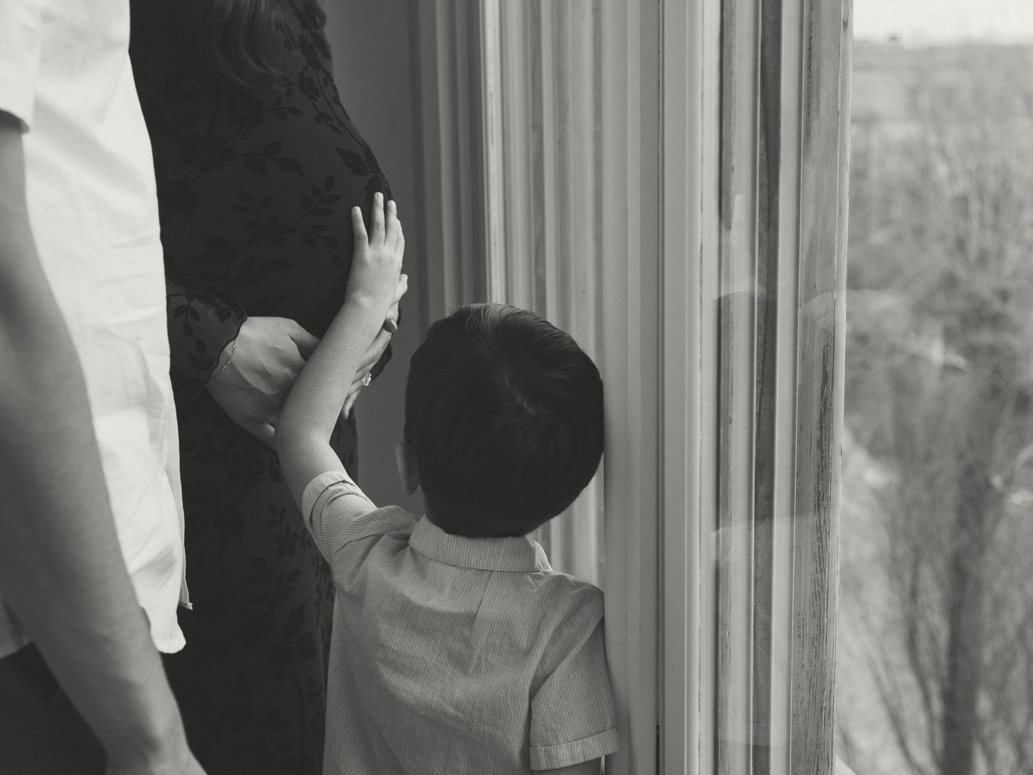 Natural light studio photos showing family moments near a window.