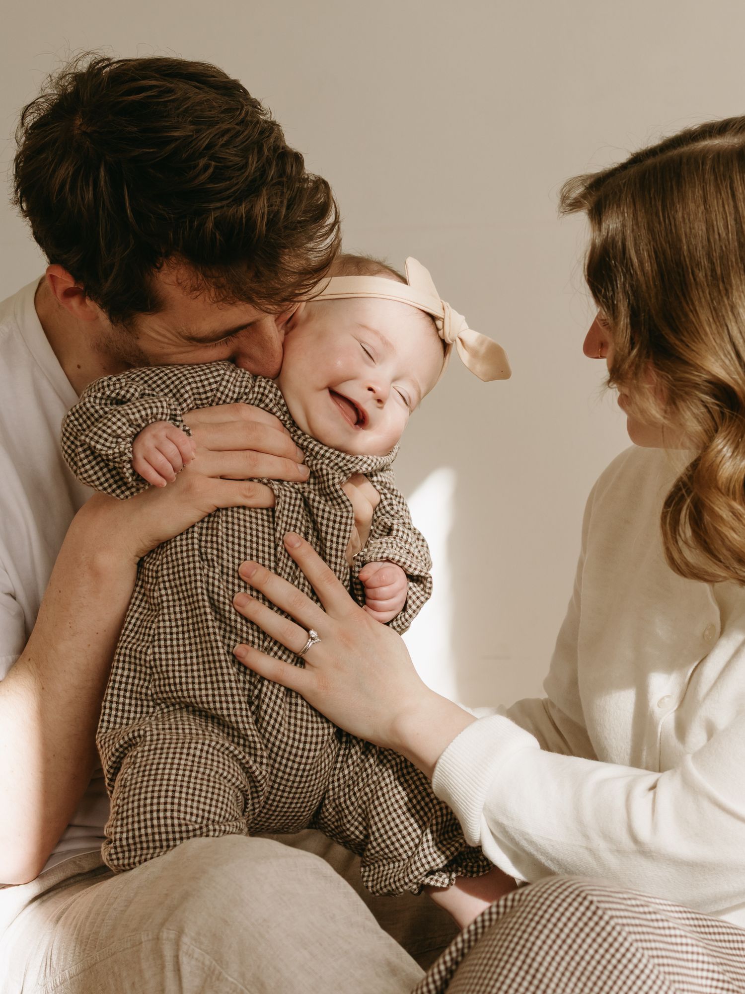 Intimate family moments captured in warm tones against neutral background with natural lighting.