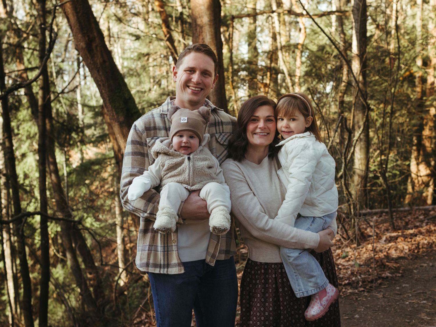 Family enjoying a sunny autumn day together in a wooded forest setting.