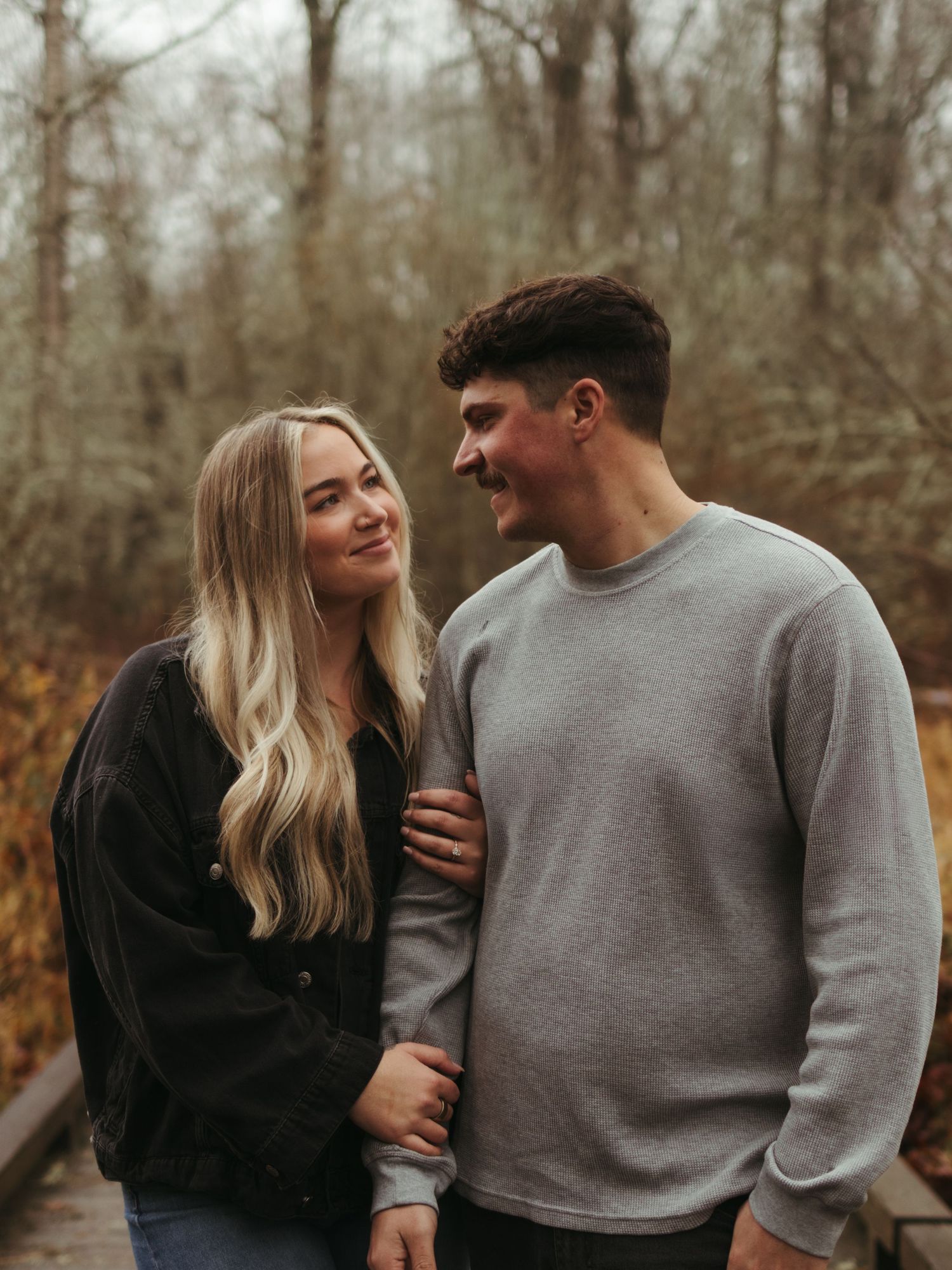 Couple laughing and embracing during autumn photoshoot in nature.
