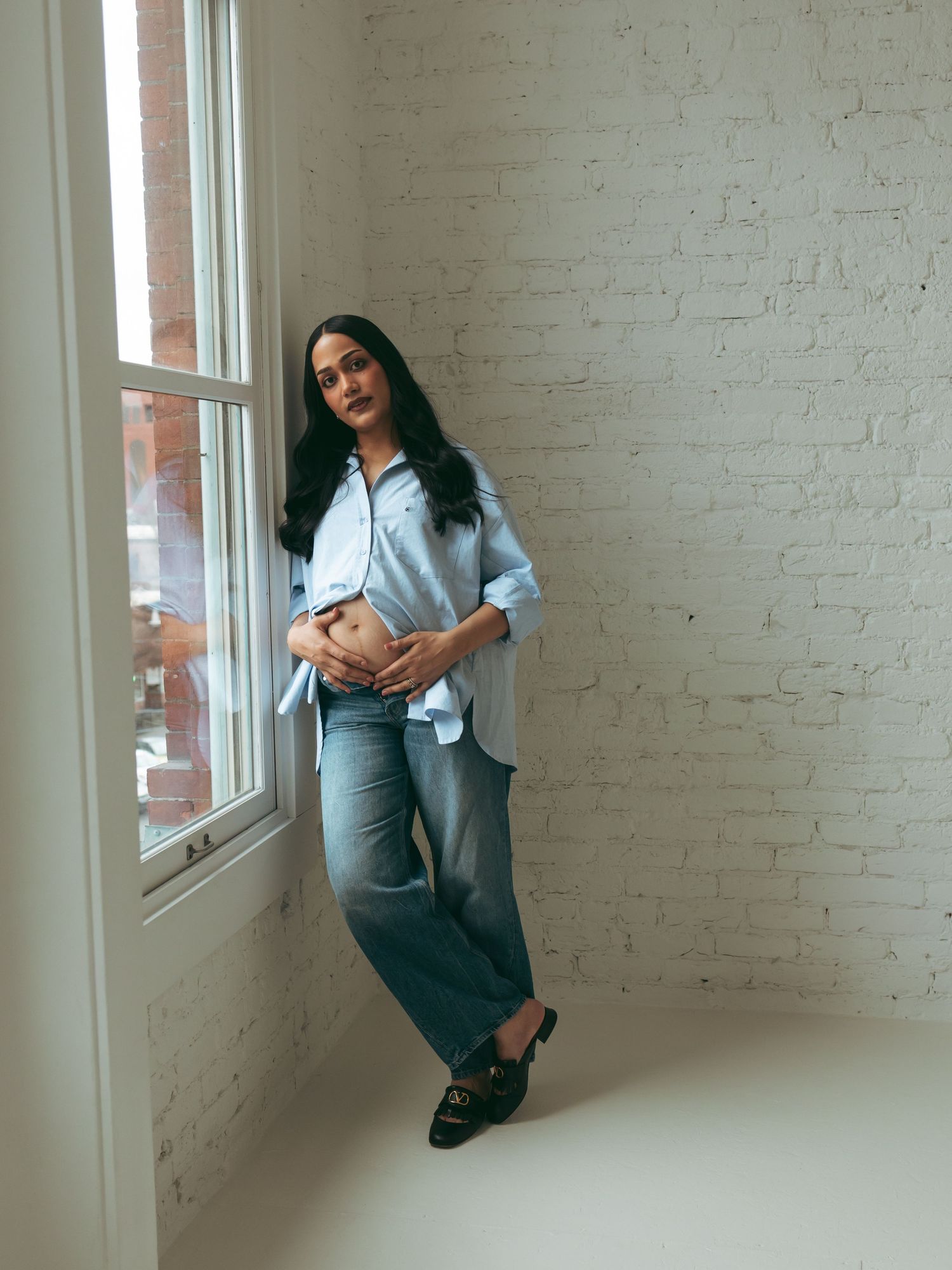 Lifestyle portraits of a woman in casual attire posing against white brick walls.