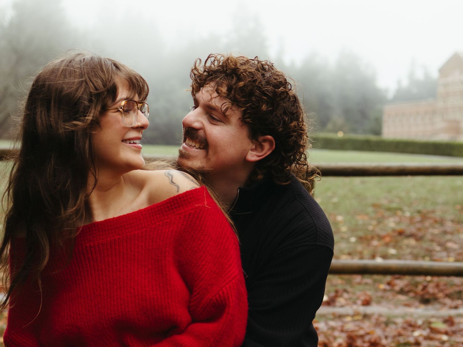 A joyful couple shares laughter while embracing on a misty autumn day.