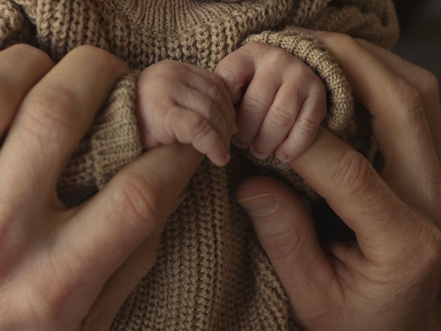 Close-up shots of hands gently touching and interacting with a knitted sweater texture.