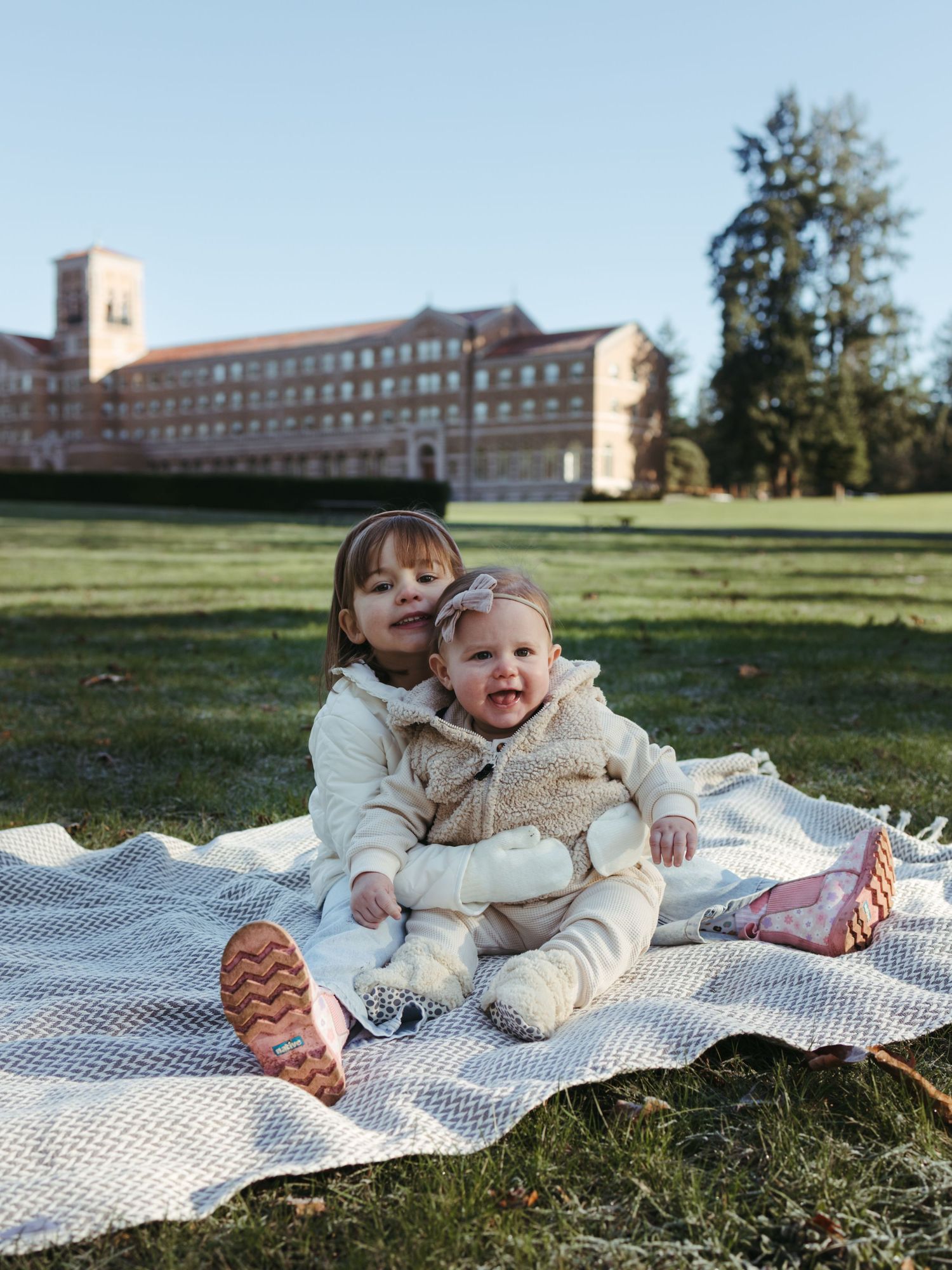 A picnic blanket spread out on grass with a large building visible in the background.
