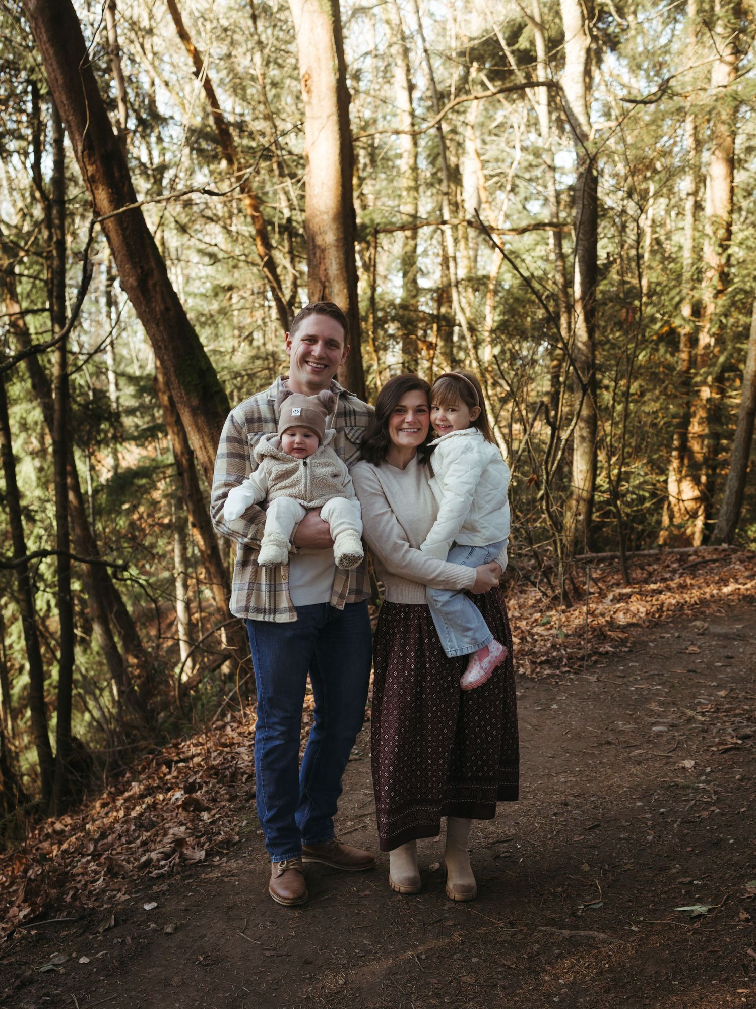 Group portrait session in a forest with sunlight filtering through trees.