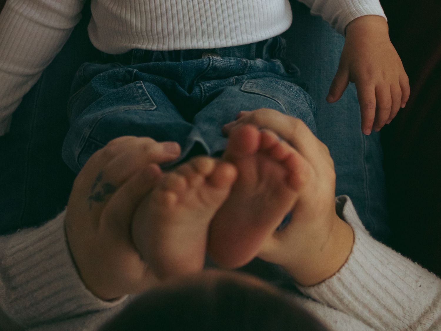 Close-up of bare feet resting on white fabric in moody lighting.