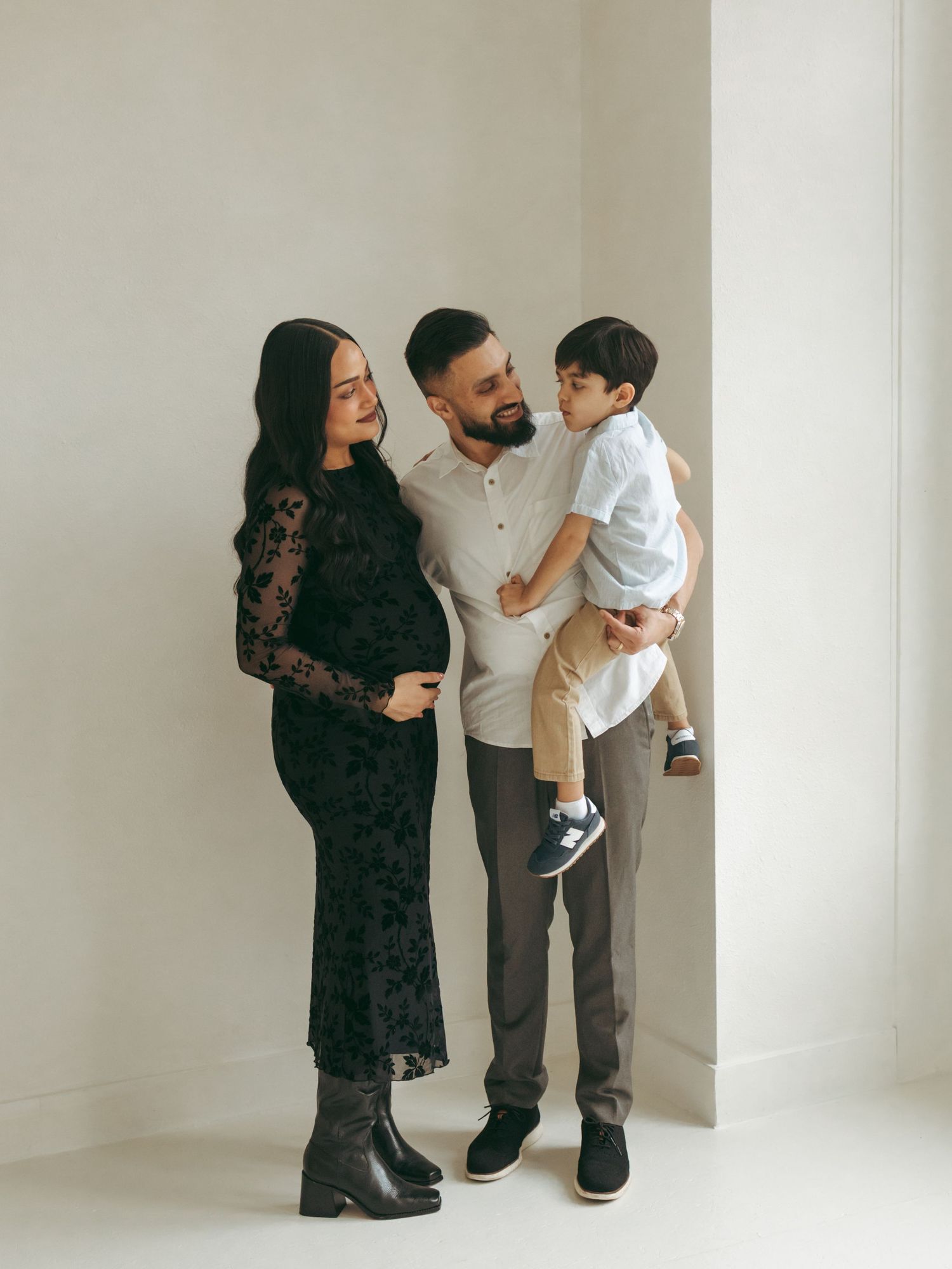 A family portrait session in a minimalist white studio space showing intimate moments together.
