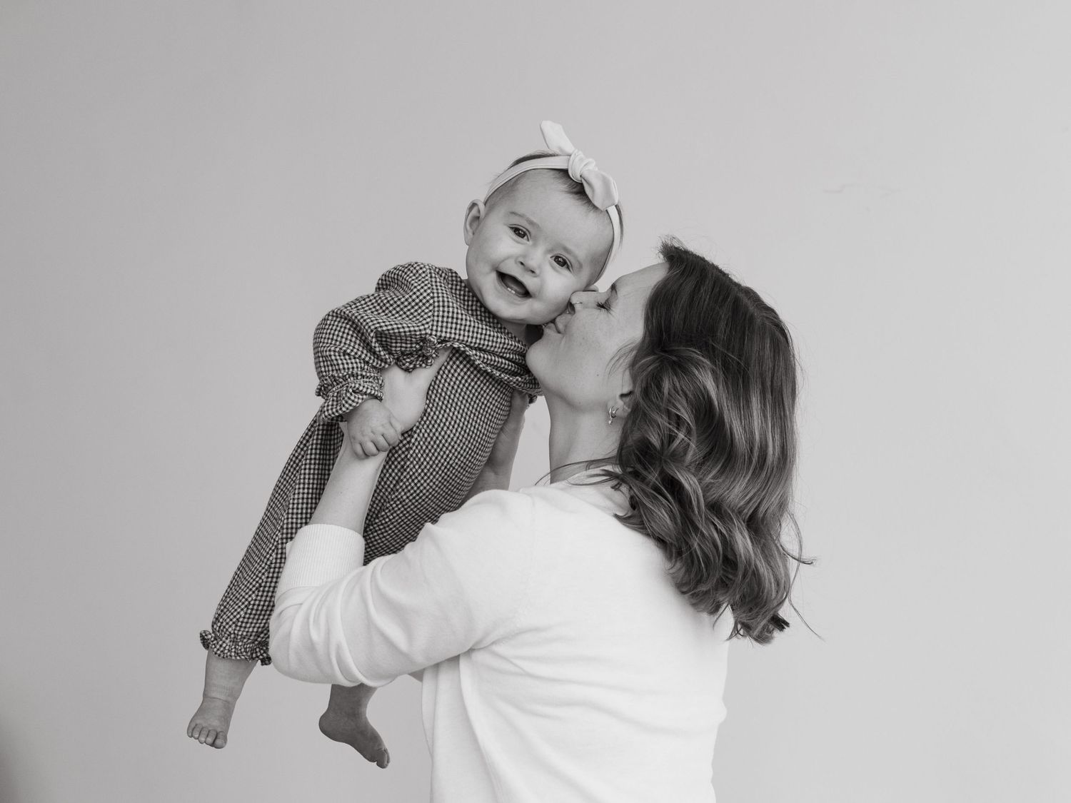 Black and white sequence of playful family interactions in a minimalist studio setting.
