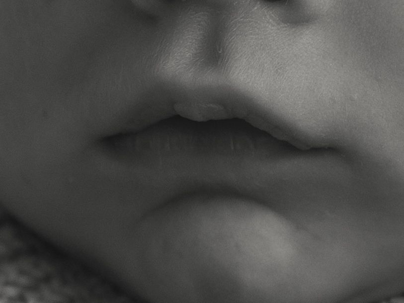 Black and white photo of tiny baby feet against white bedding.