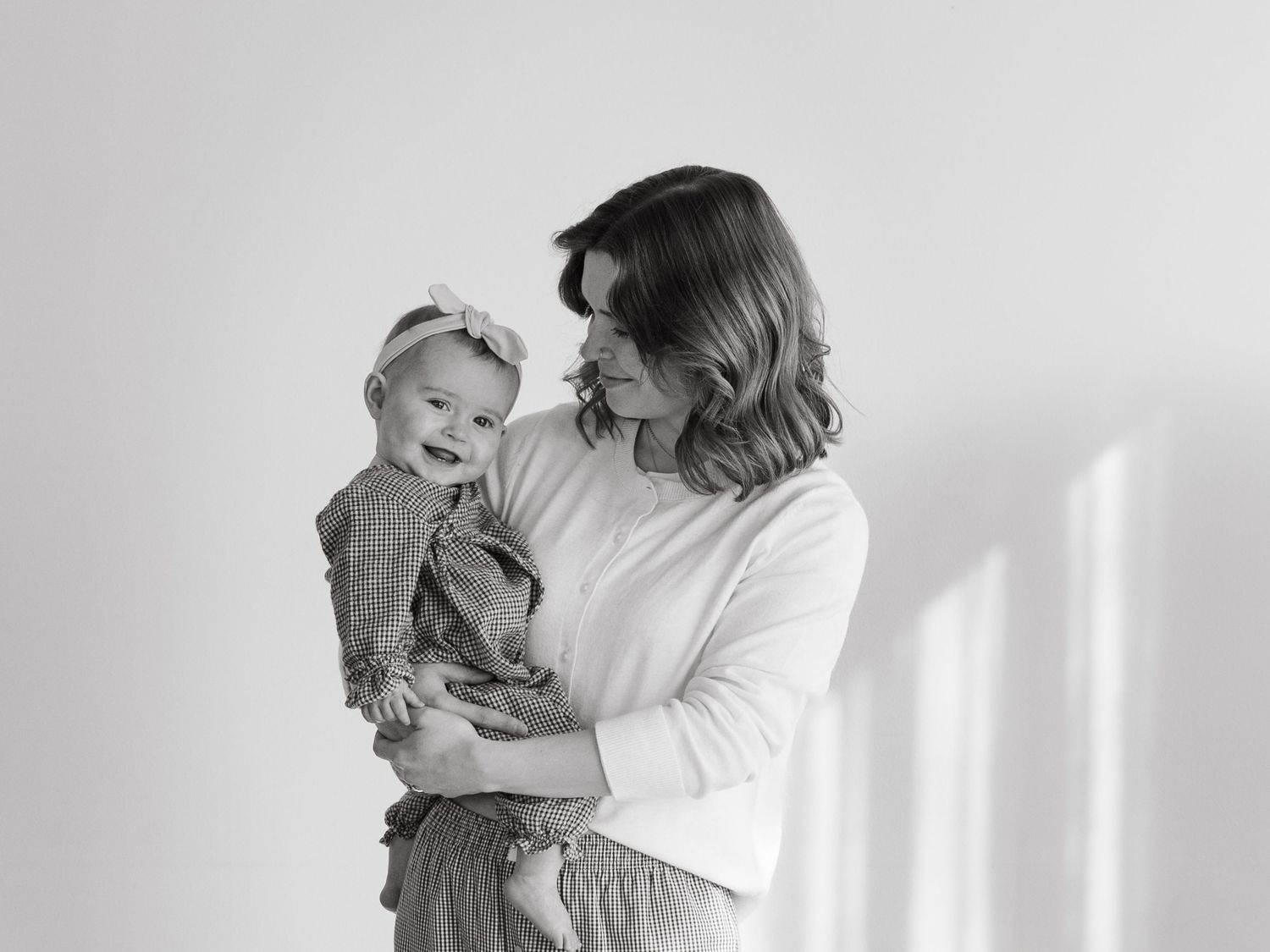 Black and white portraits capturing intimate family moments against a light backdrop.