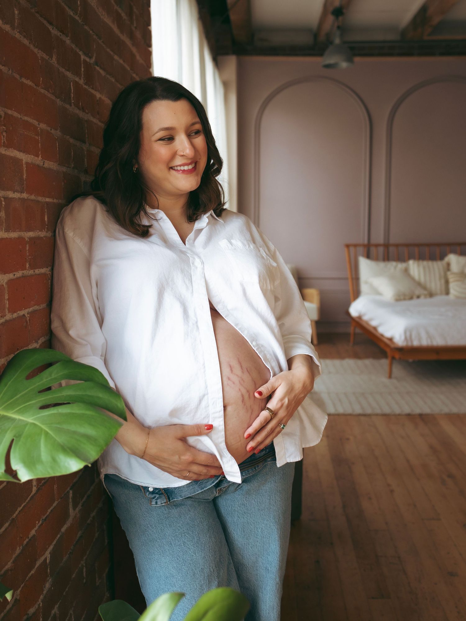 Two people in white shirts and jeans stand casually in a room with exposed brick walls and hardwood floors.
